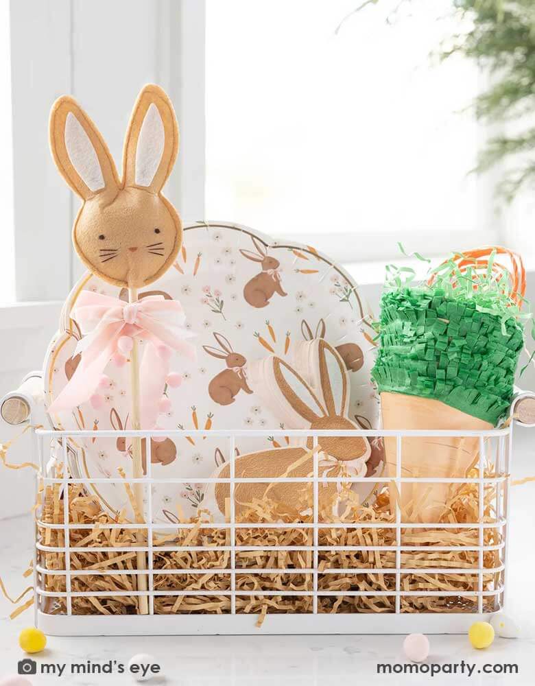 An Easter occasion bin filled with Momopartys's Easter themed tableware, treat bags and kid's gift, including the 10" x 10" scatter rabbit plates, rabbit shaped napkins, Easter bunny wand and carrot shaped treat bags by My Mind's Eye.