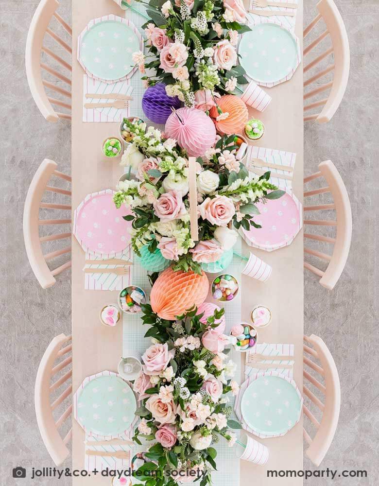 A beautiful Easter brunch table features Momopartys's Easter fun small plates along with striped party plates, cups, and napkins. In the middle of the table lays a blue gingham table runner which has baskets of spring flower arrangement and egg shaped honeycomb decorations in pastel colors, making this an adorable inspo for a Easter party tablesetting.