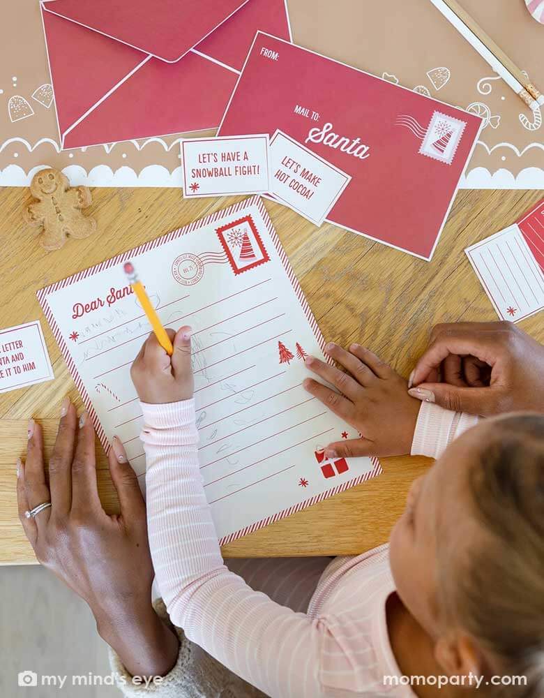 A girl writing her letter to Santa with her mom's help using Momopartys's Elf Letters to Santa stationary kit by My Mind's Eye. Each kit includes Included are 24 mini notes that your holiday friend can deliver to your loved ones, also included is one letter to Santa template that your holiday visitor can hand deliver to the big man when it is time for him to return home.
