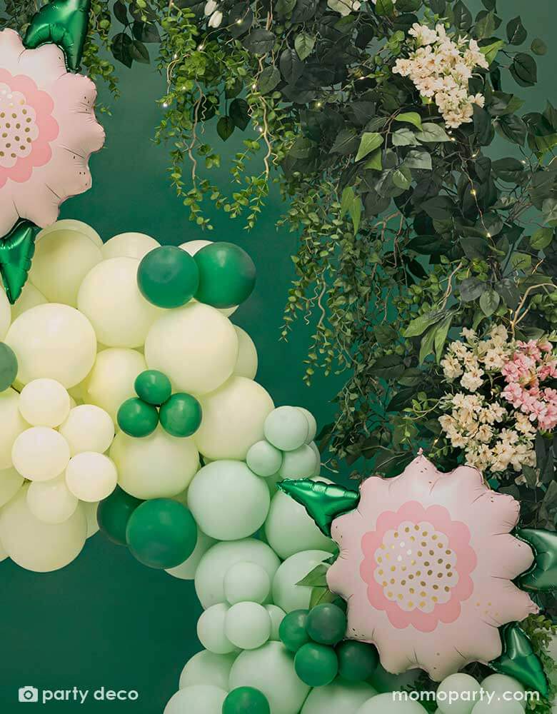 A spring inspired balloon garland in pastel yellow and mint colors peppered with some small emerald green as the green foliage adorned with two of Momopartys's 23" x 19" pink flower foil balloons. This balloon garland is next to a live leaf floral garland, makes this a great decoration for a garden party or spring inspired celebration.