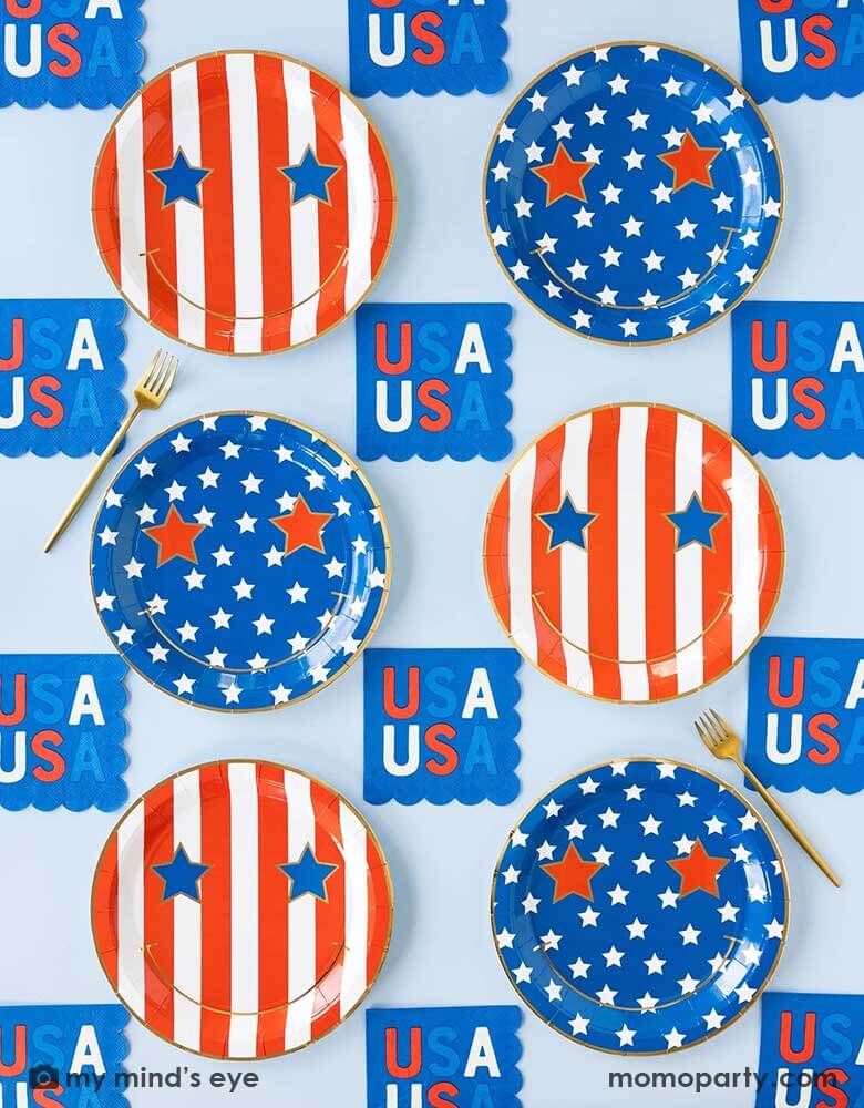 A light blue table features Momopartys's  Star & Stripe Smiley Paper Plates by My Mind's Eye. These plates come in a set of 8 in 2 designs, one with red stripes the other with blue stars. With a big smiley face and star eyes on them. Pair with 5" USA small blue napkins,  they are perfect for a retro fun 4th of July party this summer!
