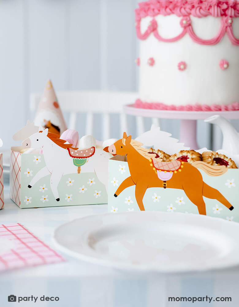 A horse/pony themed birthday party table features Momopartys's 6.7" x 4.3" x 2.95" floral pony treat boxes by Party Deco. Each snack box has some delicious treats in them including cookies and macarons. Behind the treat boxes are some party hats and a pink and white buttercream cake in vintage piping design - making this a darling inspo for girl's pony themed party.