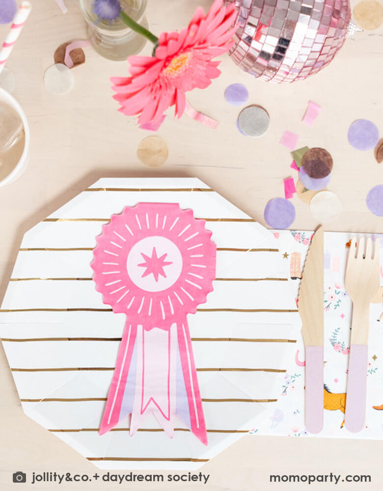 A girly pony/rodeo themed party table feature Momopartys's show ribbon shaped napkins, gold striped party plates, light pink wooden cutlery set and cowgirl motif large napkins by Daydream Society. Around the tableware there are some lilac and pink paper confetti spread-out and a small pink disco ball decoration with a pink sunflower, making this an adorable inspiration for girl's First Rodeo first birthday celebration or an adorable derby theme party for pony-loving girls!