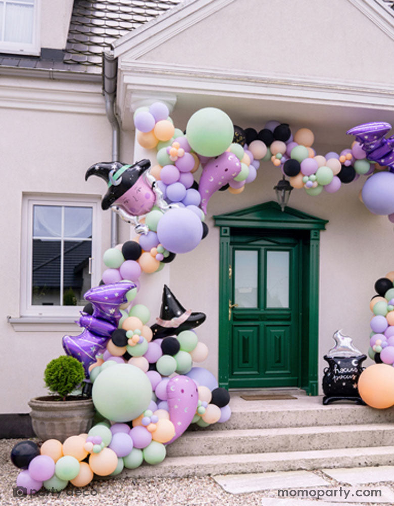 A witch inspired balloon installation at the entry door featuring Momopartys's Halloween witch themed foil balloons including the witch hat shaped foil balloon, the witch shaped foil balloon, the lilac ghost shaped balloons and the purple bat shaped foil balloons oon a pastel colored balloon garland, making this a spooky cute Halloween decoration in the not-so-spooky season!