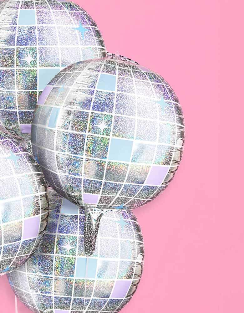 A close up shot of Momopartys's 22" Iridescent Shimmer Disco Ball Foil Balloons by Xo, Fetti. Make the whole place shimmer with these bejeweled disco ball shaped balloons. Perfect for your photo backdrop - this balloon set polishes up real nice. Each set comes with 4 disco ball 22" foil balloons Iridescent, mirrored printed finish balloons include a self-sealing valve, preventing the gas from escaping after it's inflated. The balloon can be inflated with helium to float or with a balloon air inflator. 