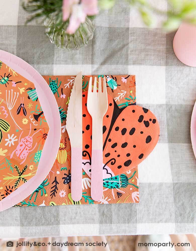 A close up shot of a cute kid's bug insect themed party table set up featuring Momopartys's backyard bug patterned plates, napkins paired with pink party cups, cutlery set and plates. With an olive green gingham tablecloth under and a beautiful flower bouquet, this makes a perfect inspiration for a modern take of a kid's bug themed celebration.