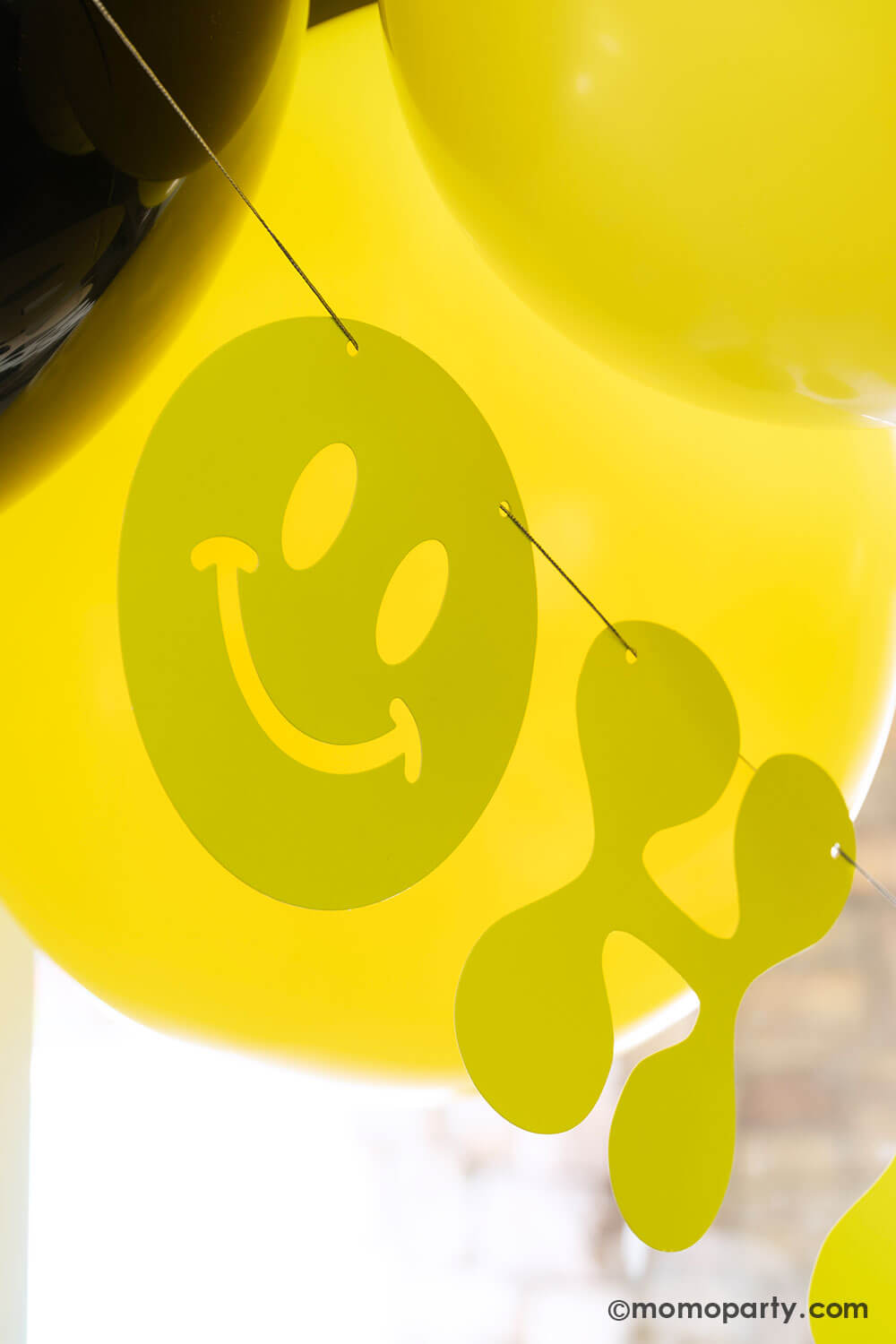 Close up of Momopartys's retro neon happy birthday banner  in bright yellow hung below some birthday party balloons. This banner is perfect for for boy's "One Happy Dude" themed first birthday, a "Two Cool" themed second birthday party or "Ten Rad Years" 10th birthday party.