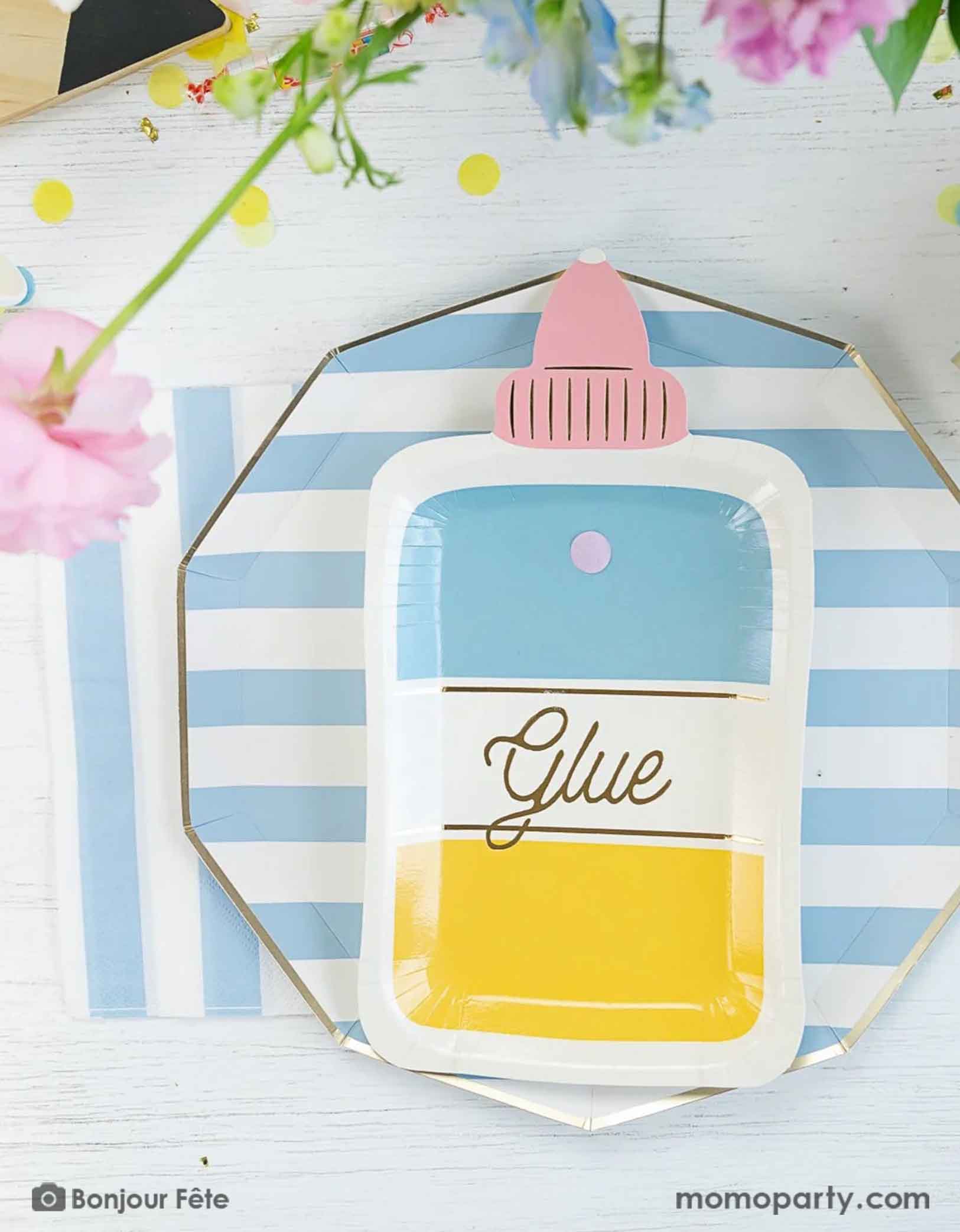 An overhead shot of a school themed tablescape featuring Momopartys's sky blue striped dinner plates and napkins paired with glue bottle shaped plate, which makes a great inspiration and idea for a school themed celebration or a back to school/first day of school party for kids.