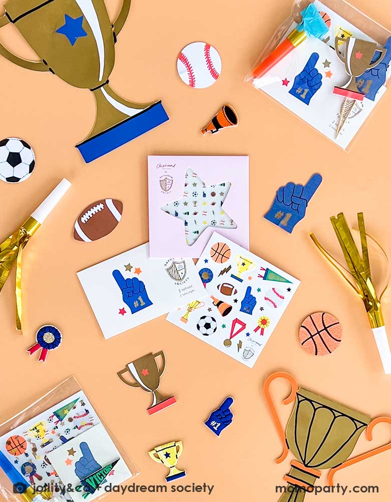 A overhead shot of some sport themed party favors from Momopartys including Good Sport Temporary Tattoos, sticker sheets, nail stickers and sports confetti including trophies, football, soccer, baseball, basketball and number one finger. With some party blowers, these make good party bag fillers for a kid's sport themed birthday party.