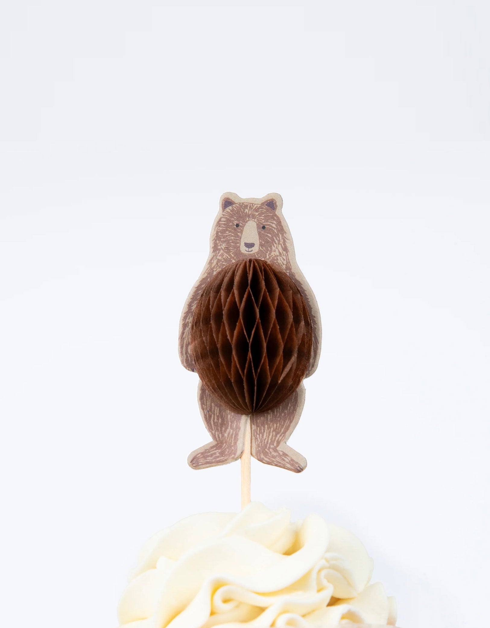 A close up shot of Momopartys's Camping Adventure Cupcake Kit by Meri Meri. This kit includes cake toppers with iconic camping characters and retro designs, teamed with checked cupcake cases. This specific cupcake topper features a honeycomb bear with a wooden cocktail sticks to easily insert the toppers into your cupcakes.