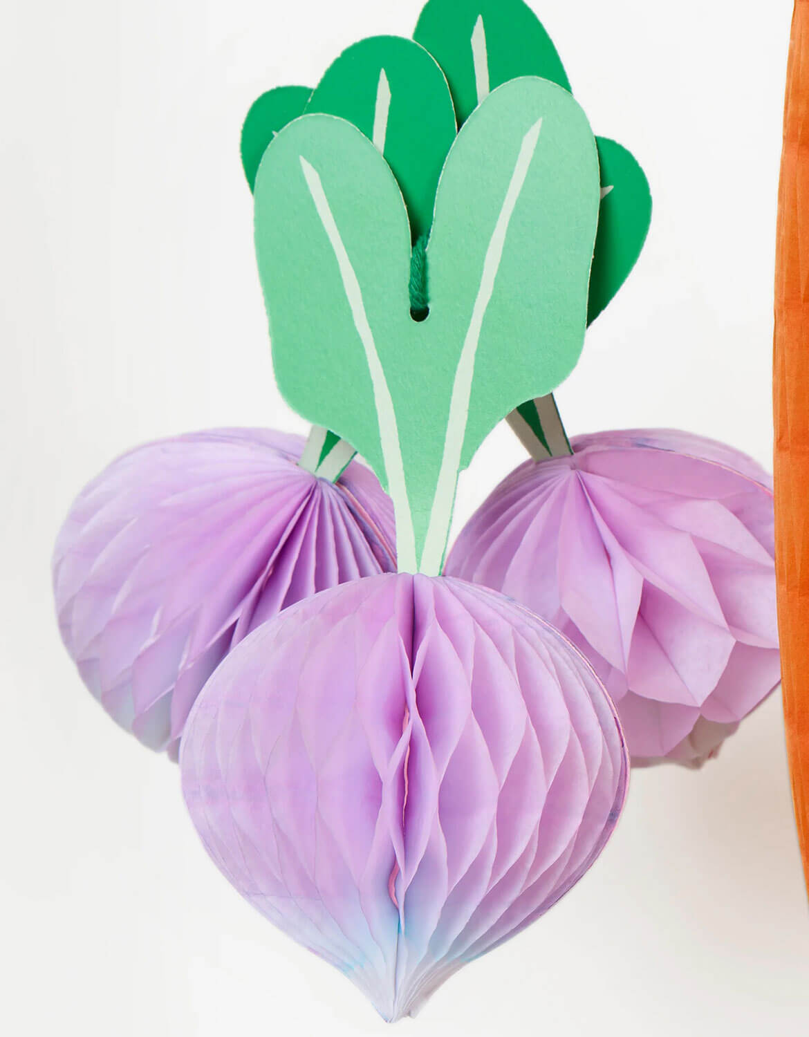 A close up of a bunch of beet hanging honeycomb decorations from Momopartys's decorative paper hanging vegetable honeycomb decoration set by Meri Meri on a white background.