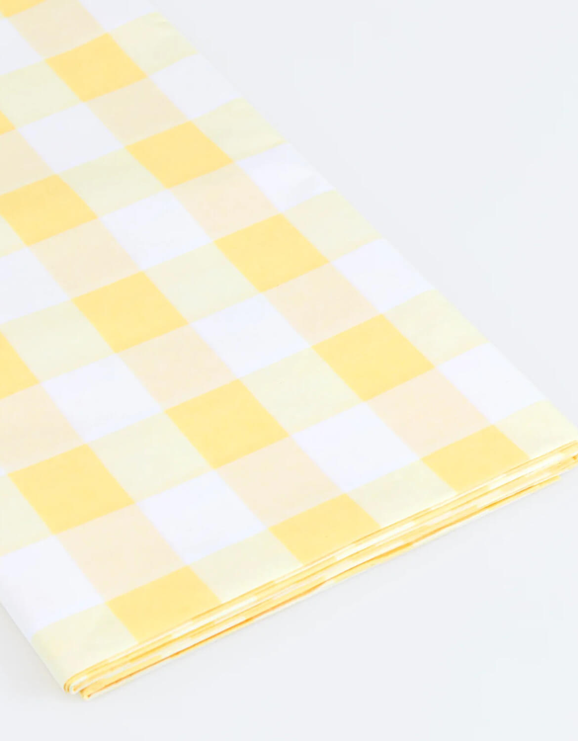 A close up shot of Momopartys's paper tablecloth with yellow and white checkered design by Meri Meri on a white background.