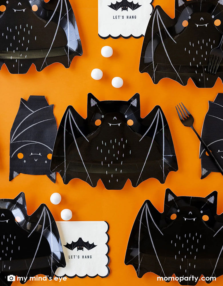 A classic Halloween black and orange table featuring Momopartys's 10.5" x 8.5" bat shaped plates, napkins and black square plates with white scalloped edge. Along the tableware, there are some black and white Halloween treats including candies, chocolates and gum balls, makes it a great party inspiration for kid's friendly Halloween party ideas.