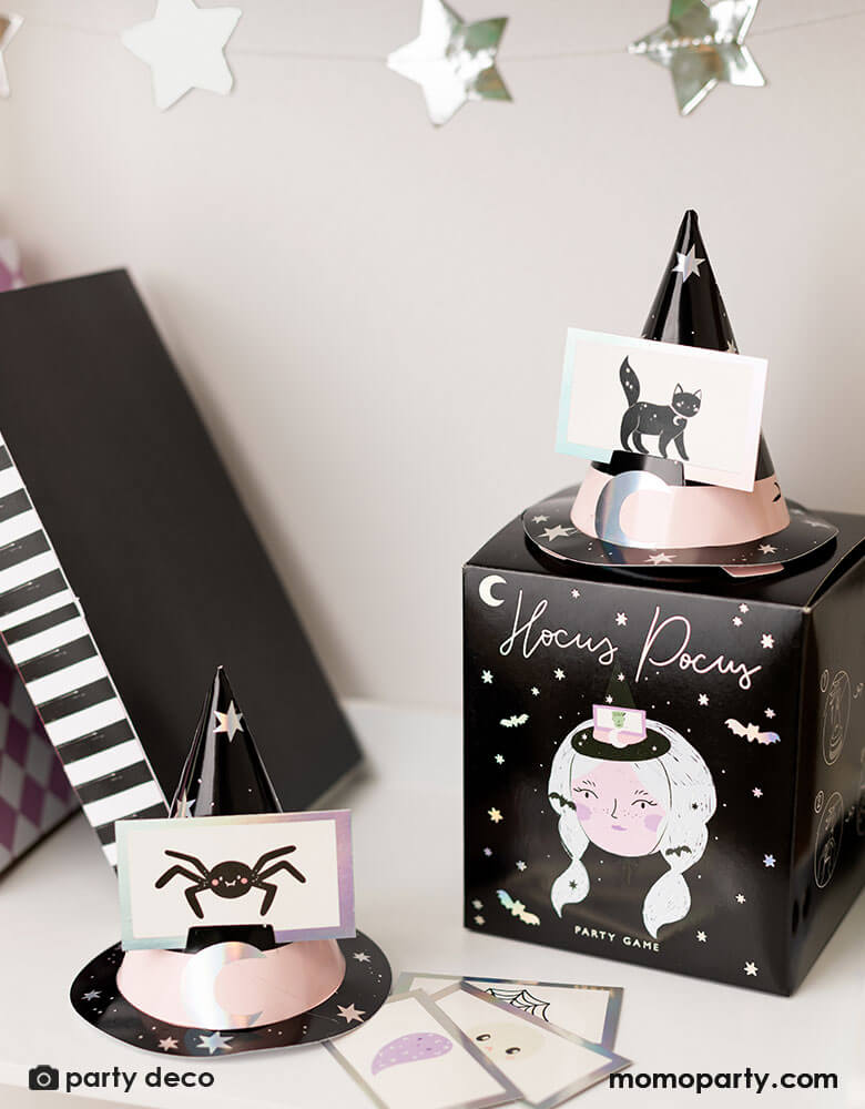 A display shelf featuring Momopartys's Momopartys's Halloween Guessing Game Set by Party Deco. Comes in a black box with a Halloween witch design on it, this set includes 6 witch hats with elastic band and 40 cards with Halloween character illustrations including Halloween witches, Dracula, spiders, black cats, ghosts, skulls, spiderweb and more.