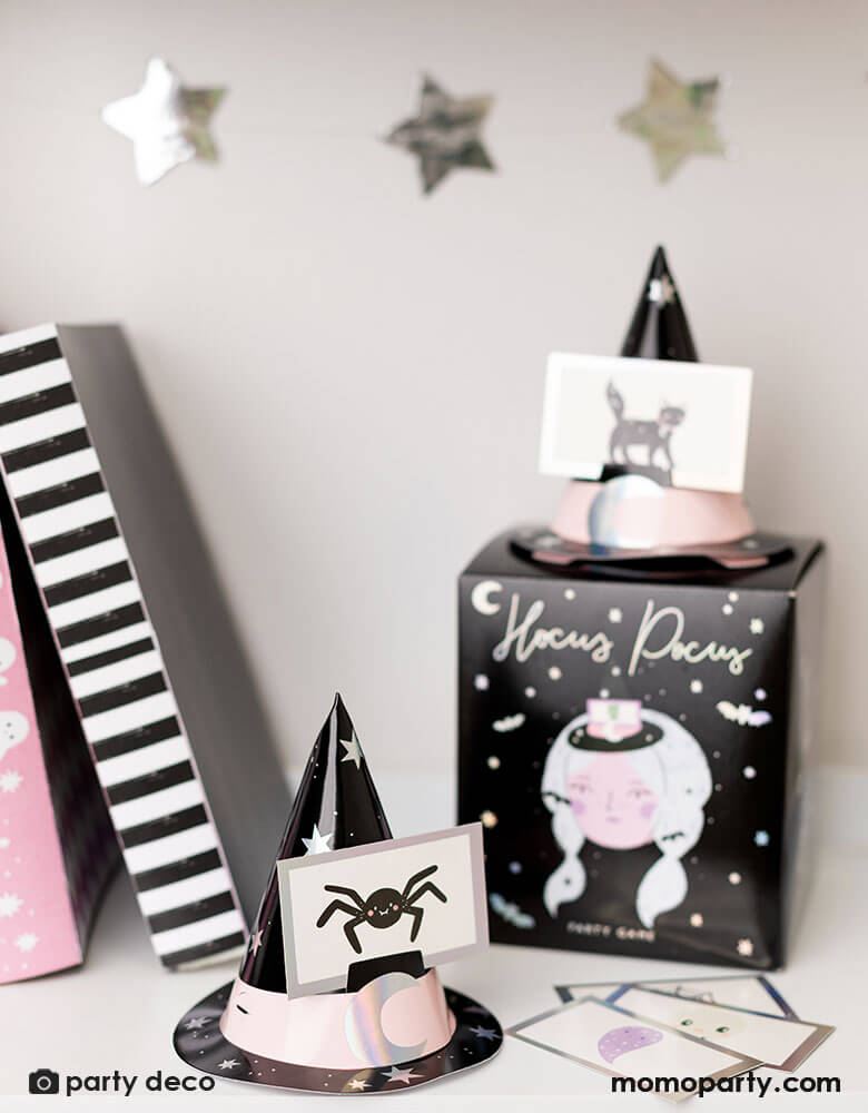 A display shelf featuring Momopartys's Momopartys's Halloween Guessing Game Set by Party Deco. Comes in a black box with a Halloween witch design on it, this set includes 6 witch hats with elastic band and 40 cards with Halloween character illustrations including Halloween witches, Dracula, spiders, black cats and more.
