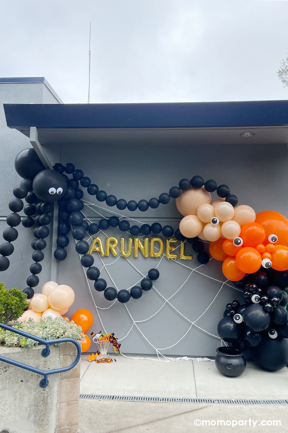Halloween Balloon garland wall decoration by Momopartys. Featuring a giant spider balloon made with two jumbo 3 ft Qualatex balloons and link balloons as the legs. On the right there's a 12 ft balloon garland in the colors of black, orange and blush in multiple sizes with 5" mini eyeball balloons adorned, it sets a spooky yet adorable scene for a kid's Halloween party or a trick-or-treat celebration!
