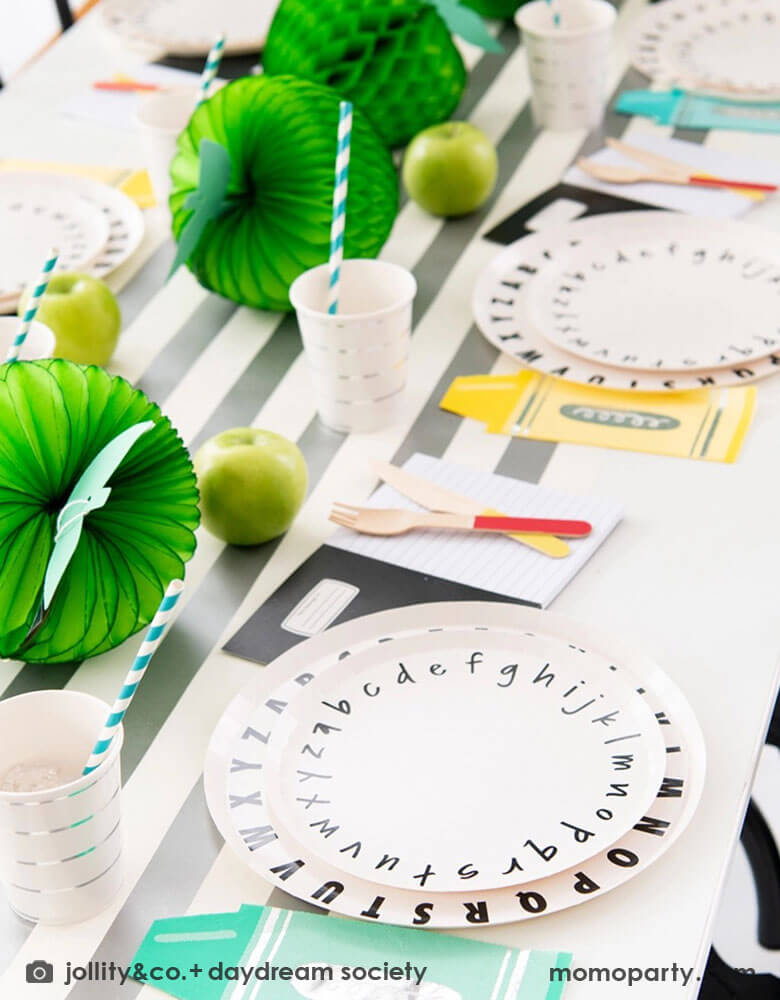 A back to school party table set up featuring Momopartys's School Days large and small Plates, along with crayon shaped napkins by Daydream Society. In the middle of the table were some lime green apple honeycombs and green balloons as the centerpiece. All in all makes a great inspiration of a school themed party or first day of school celebration!
