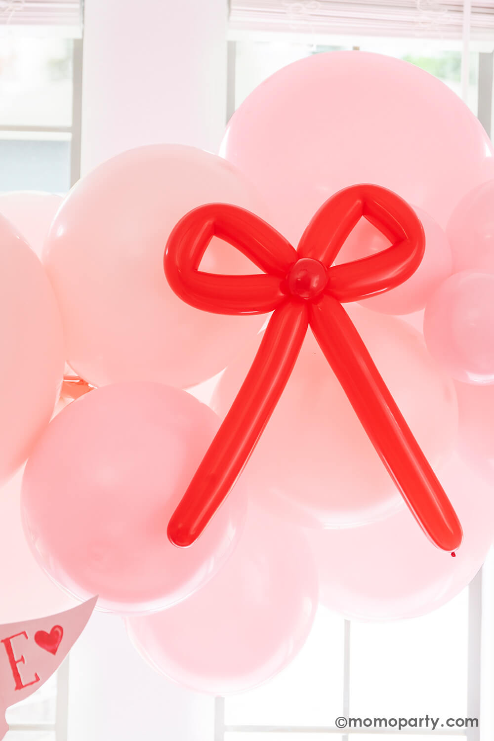 A close up shot of Momopartys's Bow-tiful Valentine's Day Party Box for 8 guests featuring a pink balloon garland with red bow balloons on it, makes it a perfectly adorable party decoration for your Valentine's Day party or Galentine's Day celebration / gathering.