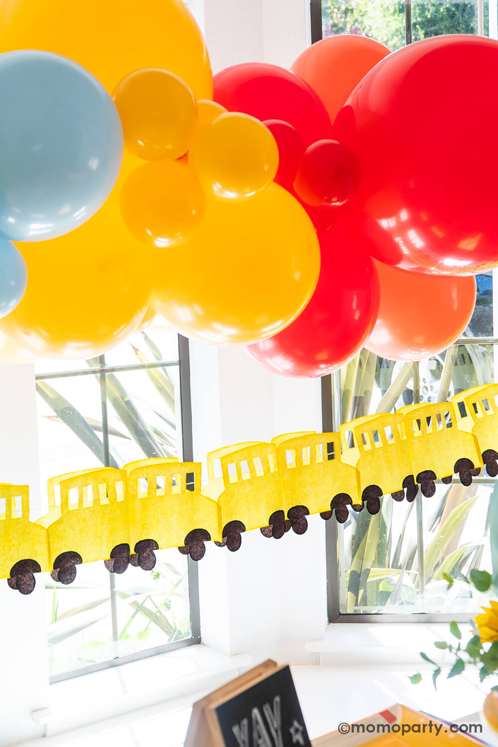 A festive back to school, first day of school party decoration featuring a colorful yet modern balloon arch of the classic school colors of red, yellow and blue, and the school bus paper garland from Momopartys. These decors are easy to put together and creates a wow factor to your child's school themed celebration, be it a back to school playdate party, a first day of school breakfast or a teacher appreciation event. 