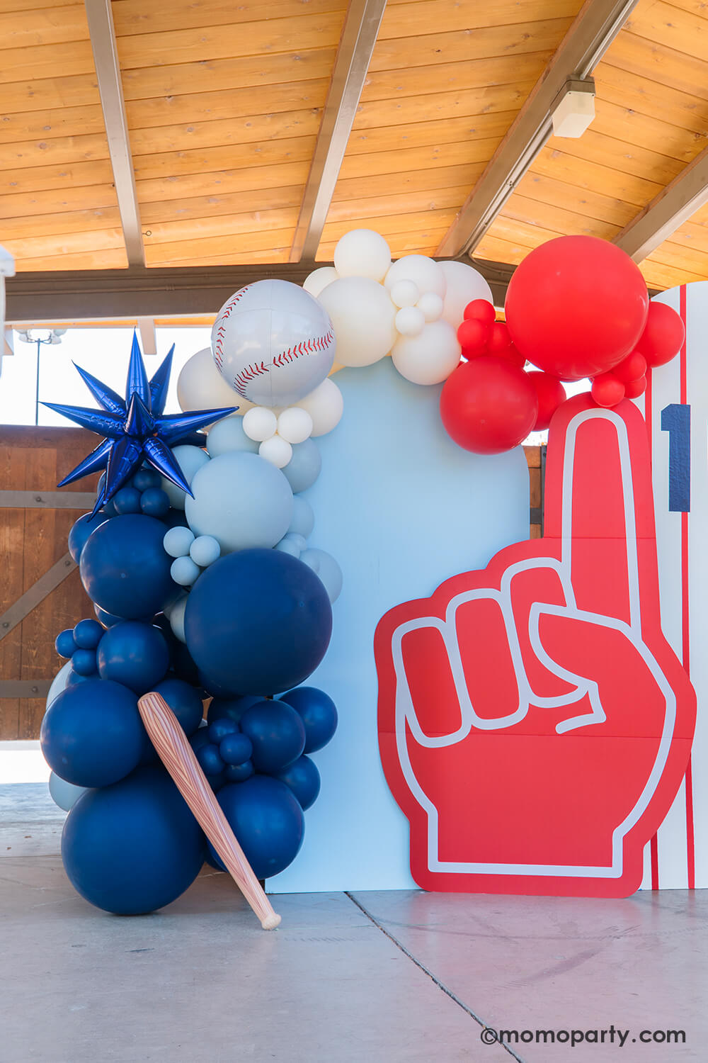 Momo Party's modern baseball-themed kids birthday party decoration featuring a baseball balloon arch with red, white, and blue balloons, blue starburst foil balloon, baseball foil balloon, foam finger, and inflatable bat — perfect for a sporty birthday celebration or all-star event backdrop.
