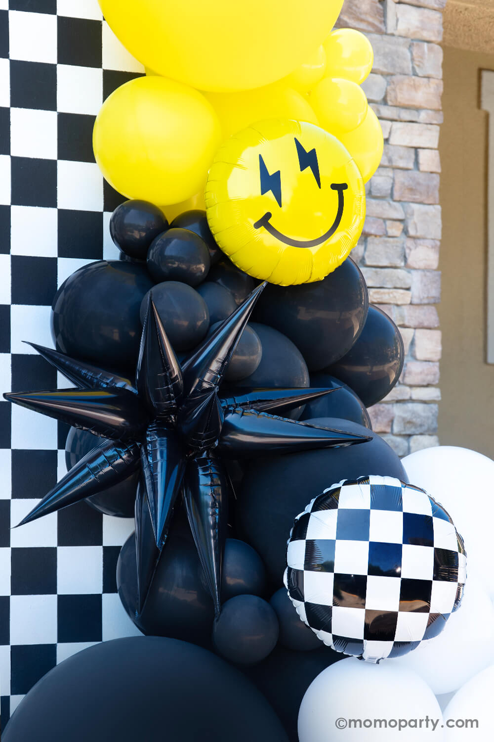 A close-up look at Momopartys's 'Cool Dude' themed Birthday Party. Featuring a captivating balloon garland in black, white, and yellow, accented by a black starburst foil balloon and a smiley face foil balloon with lightning bolt eyes. This stylish decor is complemented by a retro neon happy birthday banner. Perfect for a boy's 'One Happy Dude' themed first birthday, a 'Two Cool' themed second birthday party, 'Ten Rad Years' 10th birthday celebration, or kids birthday party for all ages.