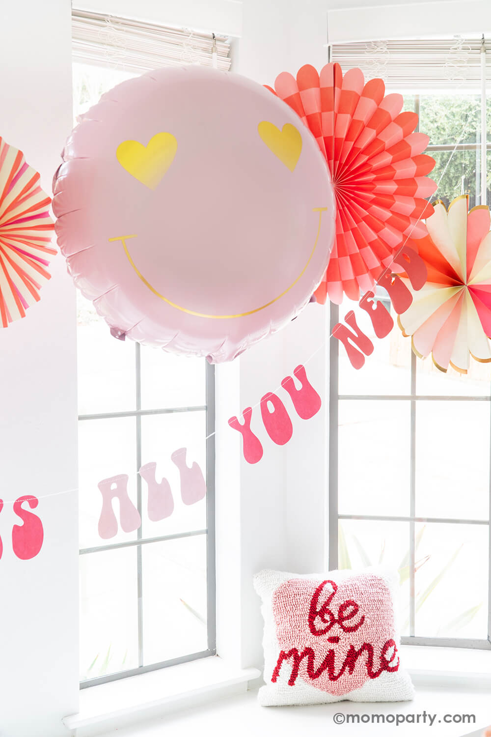 A close-up of Momopartys's Groovy Valentine's Day Party decorations, featuring My Mind's Eye Heart You Paper Fan Set with both round and heart-shaped paper fans. Paired with a Heart Eyes Love Foil Balloon and a retro-style Love Is All You Need Banner underneath, these products offer an easy and quick setup for the perfect Valentine's Day party or Groovy themed Birthday Party, or Any romantic occasion