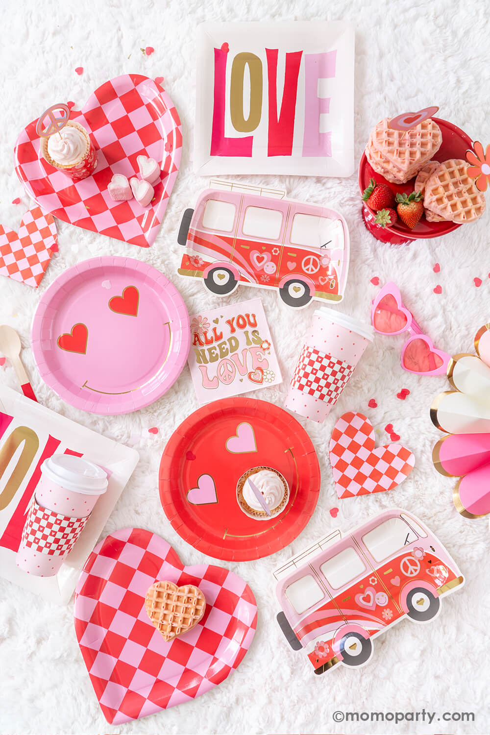 Top view of Momopartys's 2024 Retro Groovy Valentine's Day party supplies, showcasing a vibrant ensemble. Featuring Occasions by Shakira - Luv Bus Paper Plates and All You Need is Love Napkins. Additionally, Checkered Heart-Shaped Paper Plates and Checkered Heart-Shaped Napkins, Square Love Paper Plates, Heart Eyes Paper Plates, Red Checks To-Go Cup Set, and Women’s Pink Heart Shaped Party Sunglasses. Some heart-shaped wafers as treats complete the lively and nostalgic retro groove theme