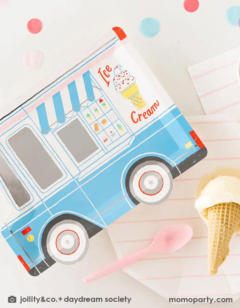 A festive party table featuring Momopartys's 10.5″ x 8″ Ice Cream Truck Plate by Daydream Society. Next to the ice cream truck plate there were a pink striped plate and napkin holding a scoop of ice cream in a waffle cone.