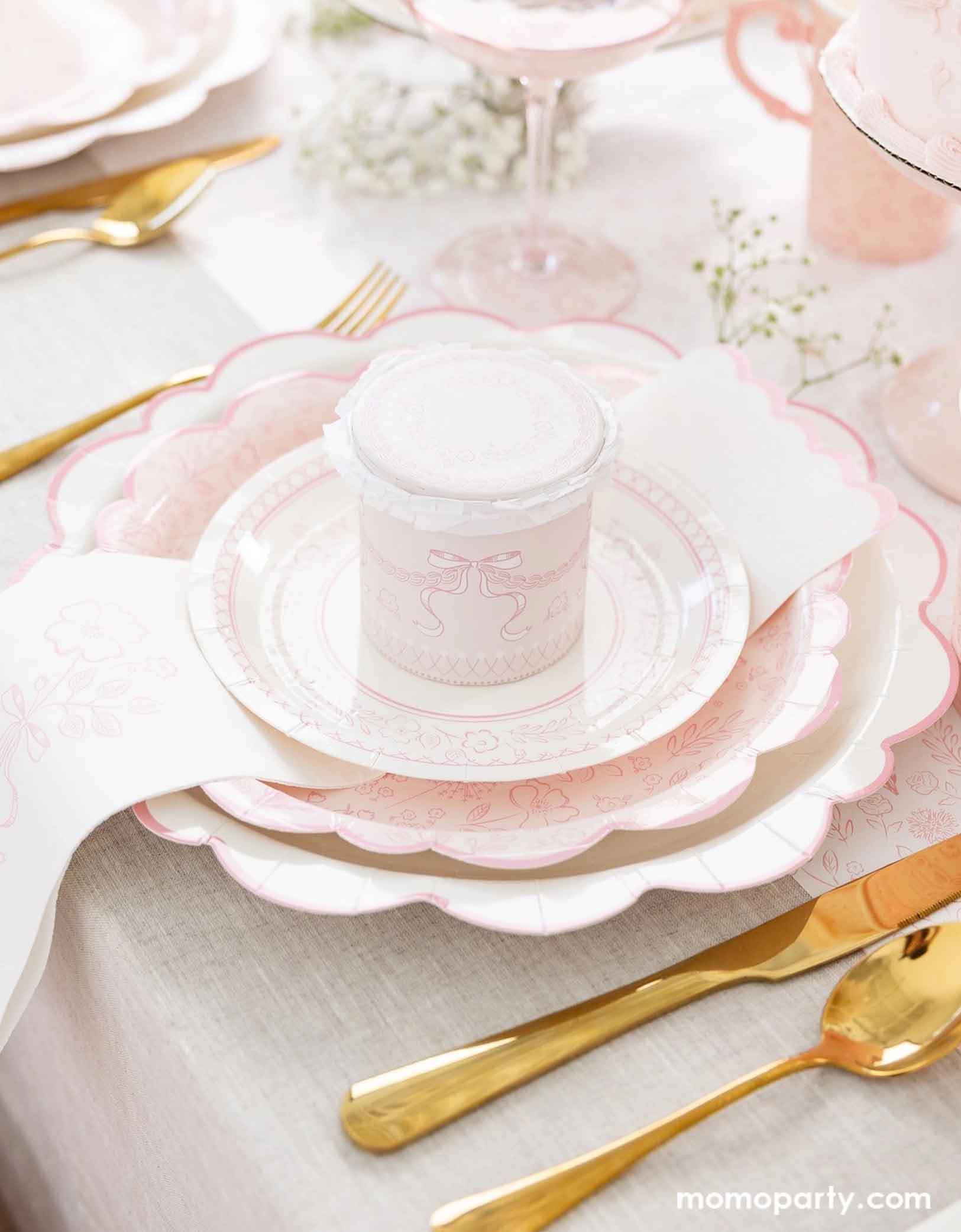 An elegant placeset featuring Momopartys's Pink Pembroke tableware collection including the 12" Pembroke Pink Edge Scallop Plate paired, 9" Pembroke Pink floral Plate, 7" Pembroke Pink Plate, Pembroke Pink napkin and the matching party cup. With the gold foil utensil set, a pretty floral arrangement and a pink champagne glass, this table setting is perfect for an Easter celebration or Mother's Day party.