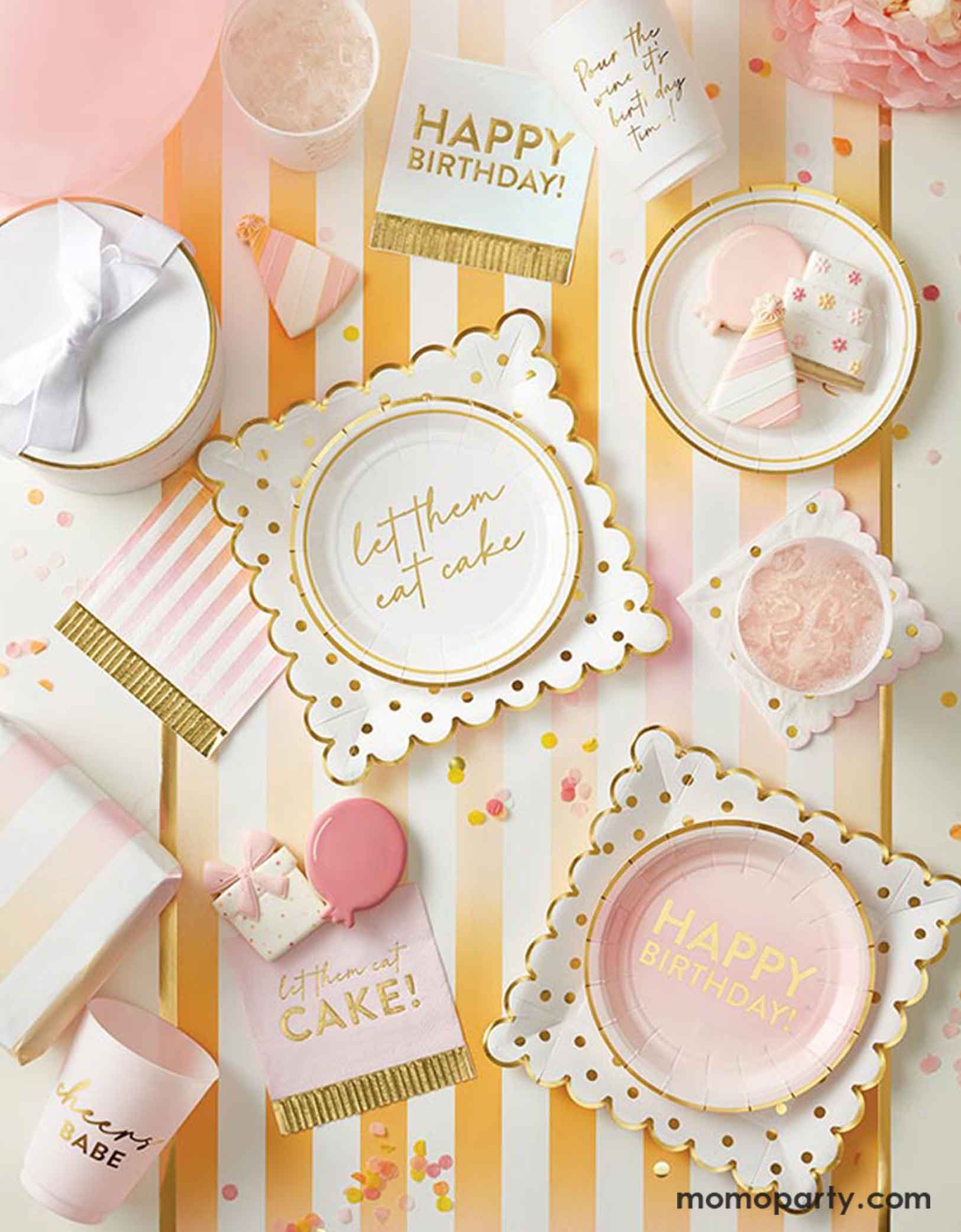 A cheerful and festive gold and pink themed birthday party table setting featuring birthday party supplies from Momopartys including gold foil polka dotted dinner plates, Happy Birthday gold foil fringe napkins, cabana ombre striped small fringed napkins , matching party cups and striped table runner. Making this a perfect setting for a girly summer-inspired birthday party bash. 
