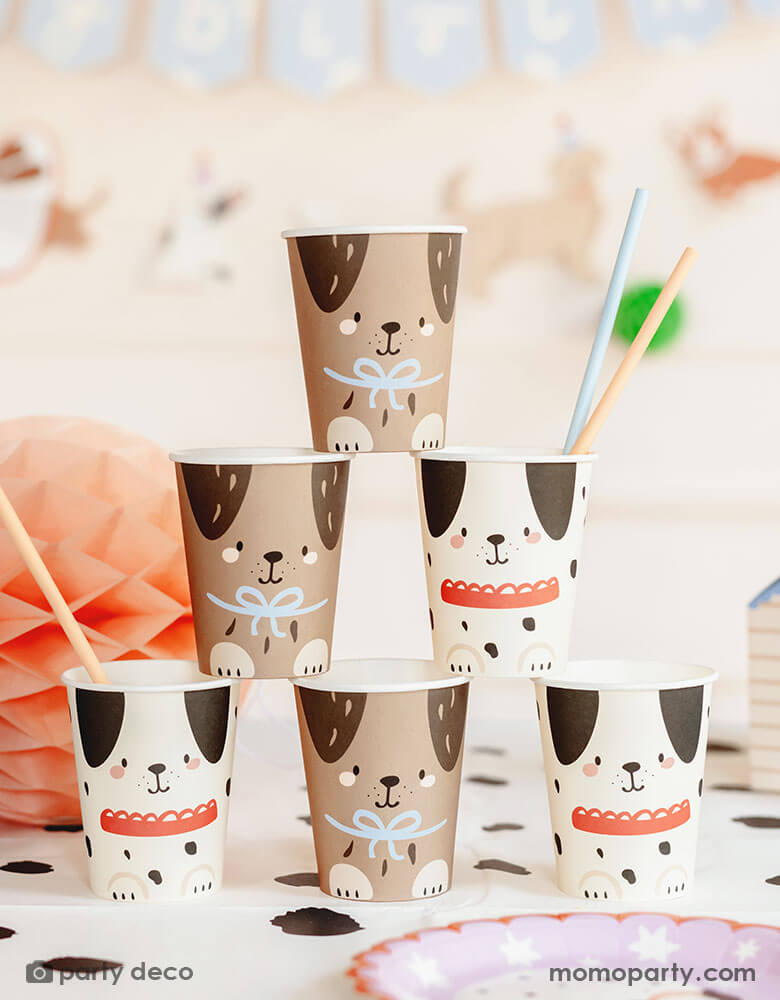 An adorable dog puppy themed birthday party table featuring Momopartys's 7.4 oz Dog Party Cups by Party Deco. These cups come in 2 designs one in cream color and the other in brown with adorable dog design on it are stacked up as a cup tower. With the Dalmatian dot tablecover underneath, pastel honeycomb decorations around the table and a happy birthday banner in the back, this makes a cute scene for kid's dog themed birthday party celebration.