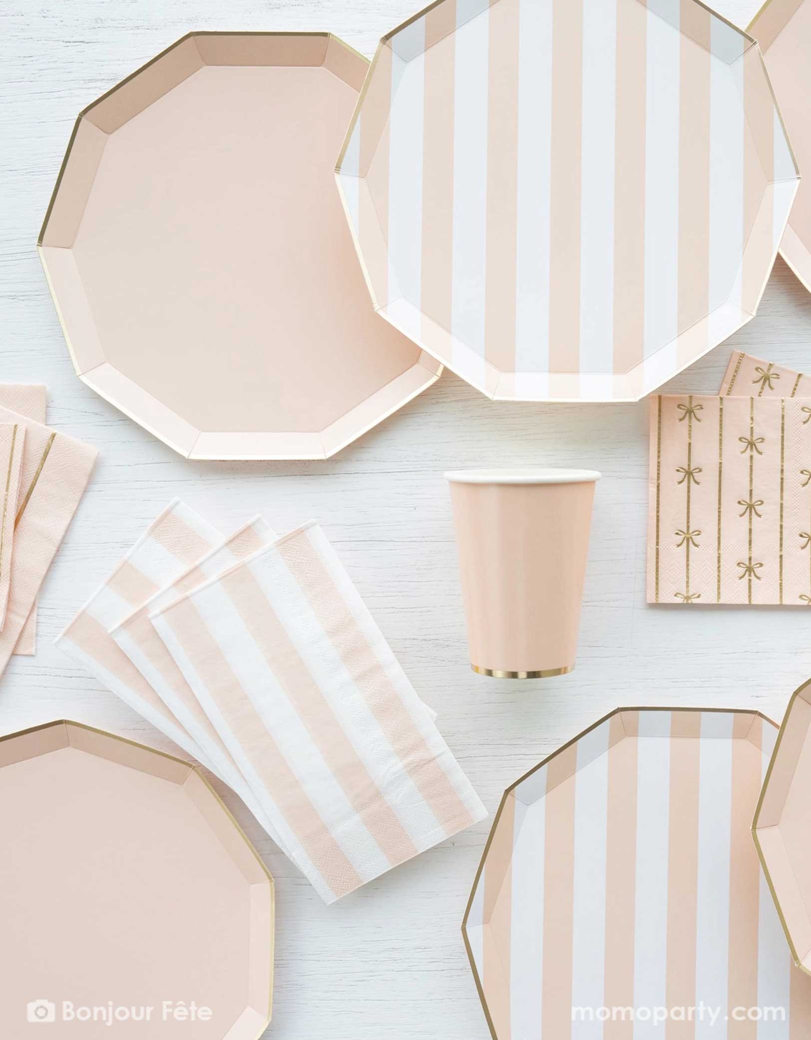 An overhead shot of a party table filled with Momopartys's pastel peach themed party tableware including sweet peach cabana striped decagon dinner plates, napkins and pastel peach dinner plates in decagon shape with matching napkins with bows and party cups - a great collection for girl's birthday, an Easter celebration or a baby girl shower. 