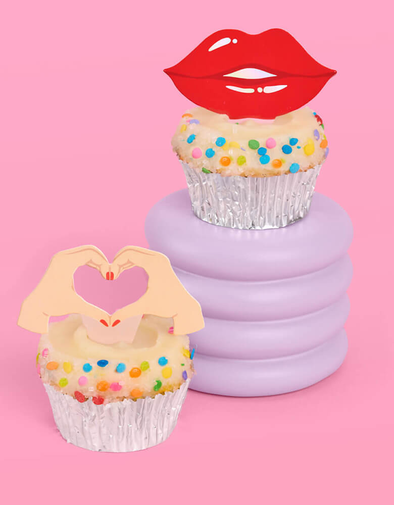 Three birthday cupcakes adorned with Momopartys's Era's Party Cupcake Toppers by Xo, Fetti. Comes in a set of 24, these Taylor Swift-themed dessert/cupcake toppers are with iconic designs including butterflies, red lips, disco balls, cassettes, guitar picks and heart hand symbols. They're perfect for to celebrate your Swiftie girl's special birthday. 