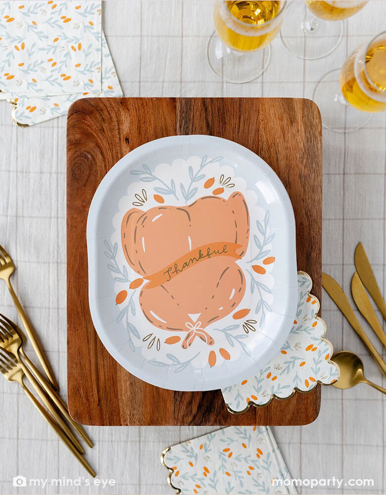 An overhead shot of Momopartys's 10" roasted turkey plate on a chopping board surrounded by tableware, champaign glasses and gingham checkered tablecloth - a perfect setting for a Thanksgiving gathering table this fall.