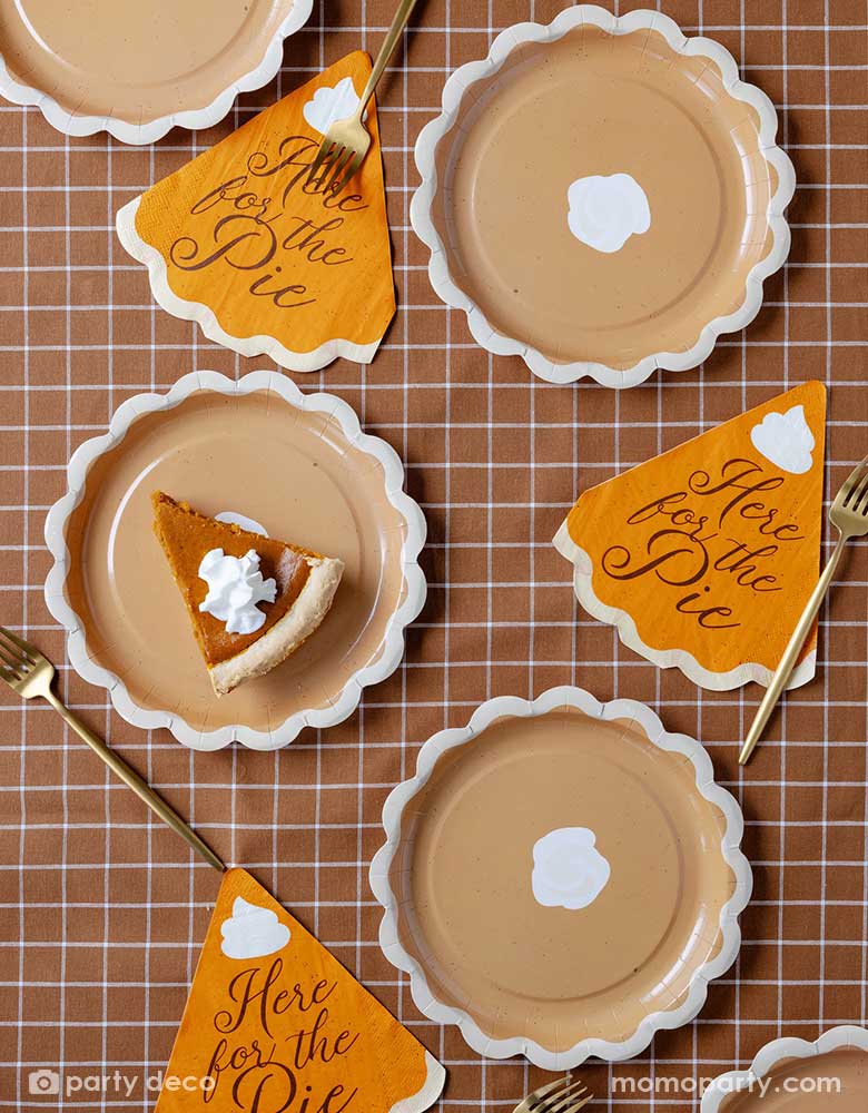 A fall inspired party tablescape featuring Momopartys's pie shaped plates with "Here for the pie" pie shaped napkins on a brown gingham checkered tablecloth. Making this a perfect inspo for a Thanksgiving or Friendsgiving gathering table setting this autumn season.