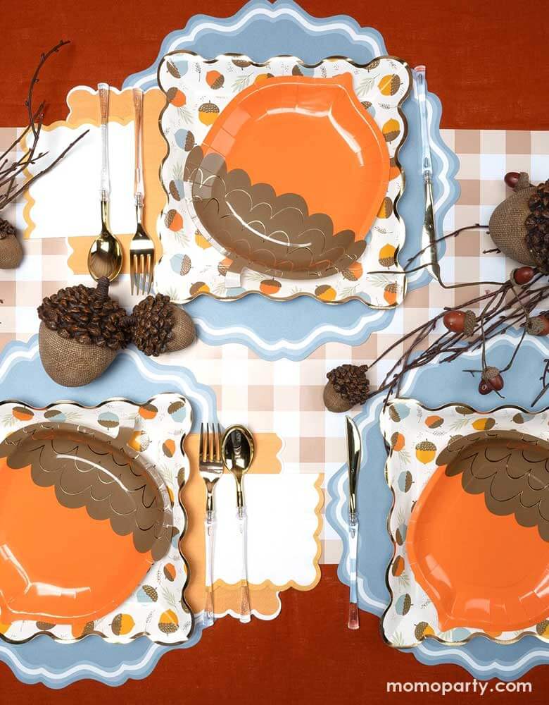 A beautiful fall tablescape featuring Momopartys's fall themed tableware including the acorn shaped paper plates, orange napkins and brown gingham table runner, with acorn bouquet and decorations, this makes a great inspo for a fall party or Thanksgiving gathering table decoration idea. 