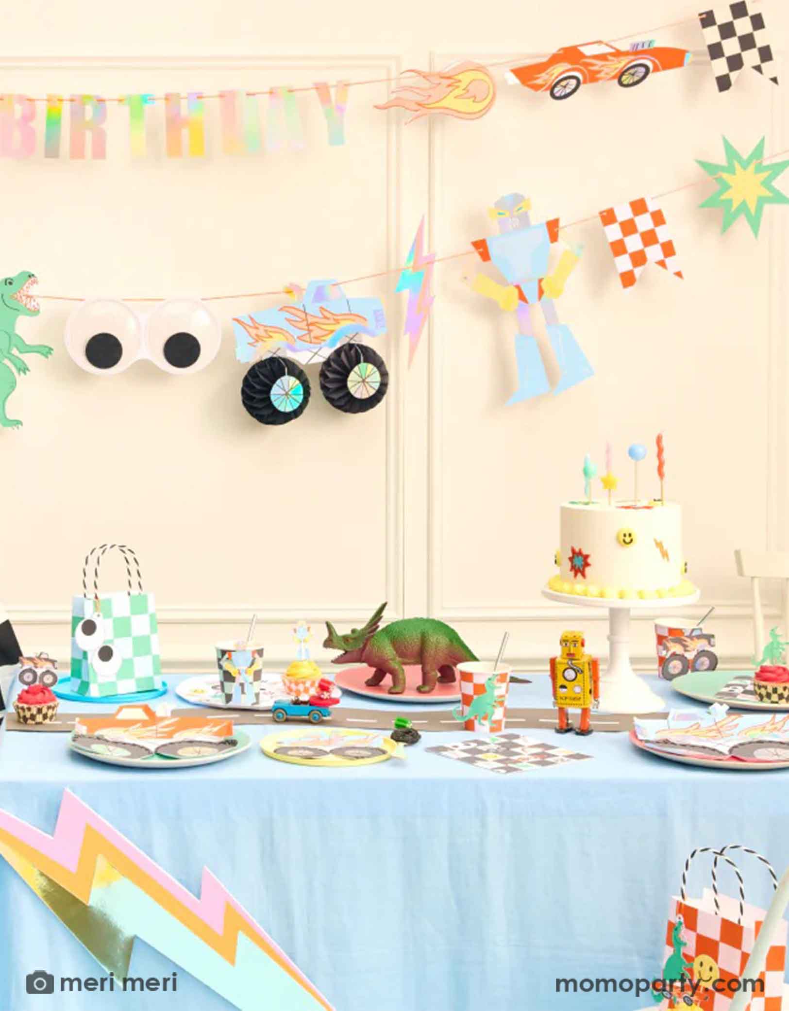 A fun themed kid's birthday party decorating set up featuring Momopartyss Momopartys's Toybox Party Collection by Meri Meri. With the retro inspired and checker board designs,  featuring elements from kid's toy boxes including dinosaurs, monster trucks, race cars, googly eyes. robots and lightning bolts, these party supplies including a large party garland on the way with HAPPY BIRTHDAY message, and a table of fun and festive party tableware including party plates, cups, napkins and favor bags.