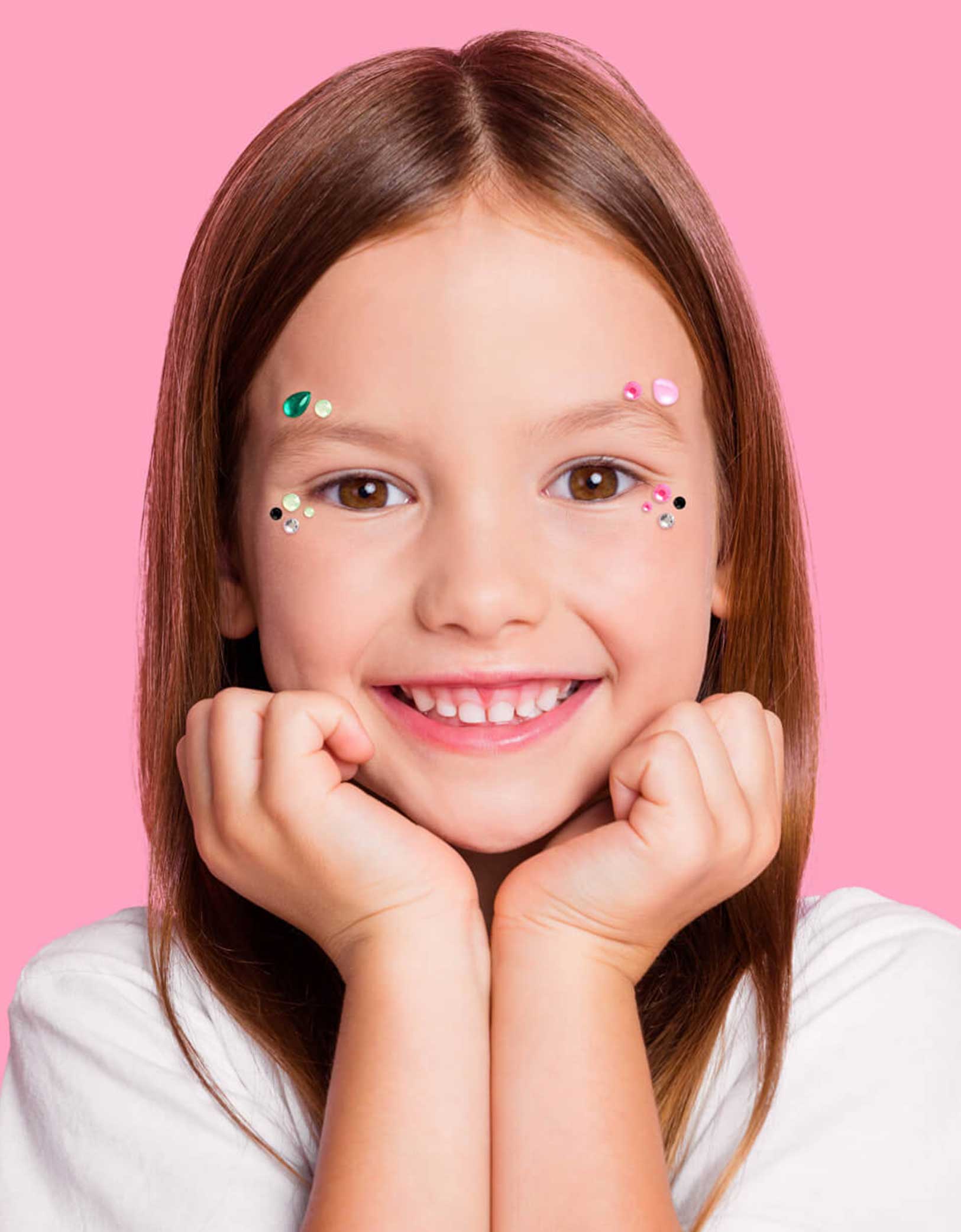 A young girl with Momopartys's Wicked themed gem stickers on her face against a pink background. Perfect for girl's Wicked themed birthday party, witch themed Halloween bash or a magical gathering.