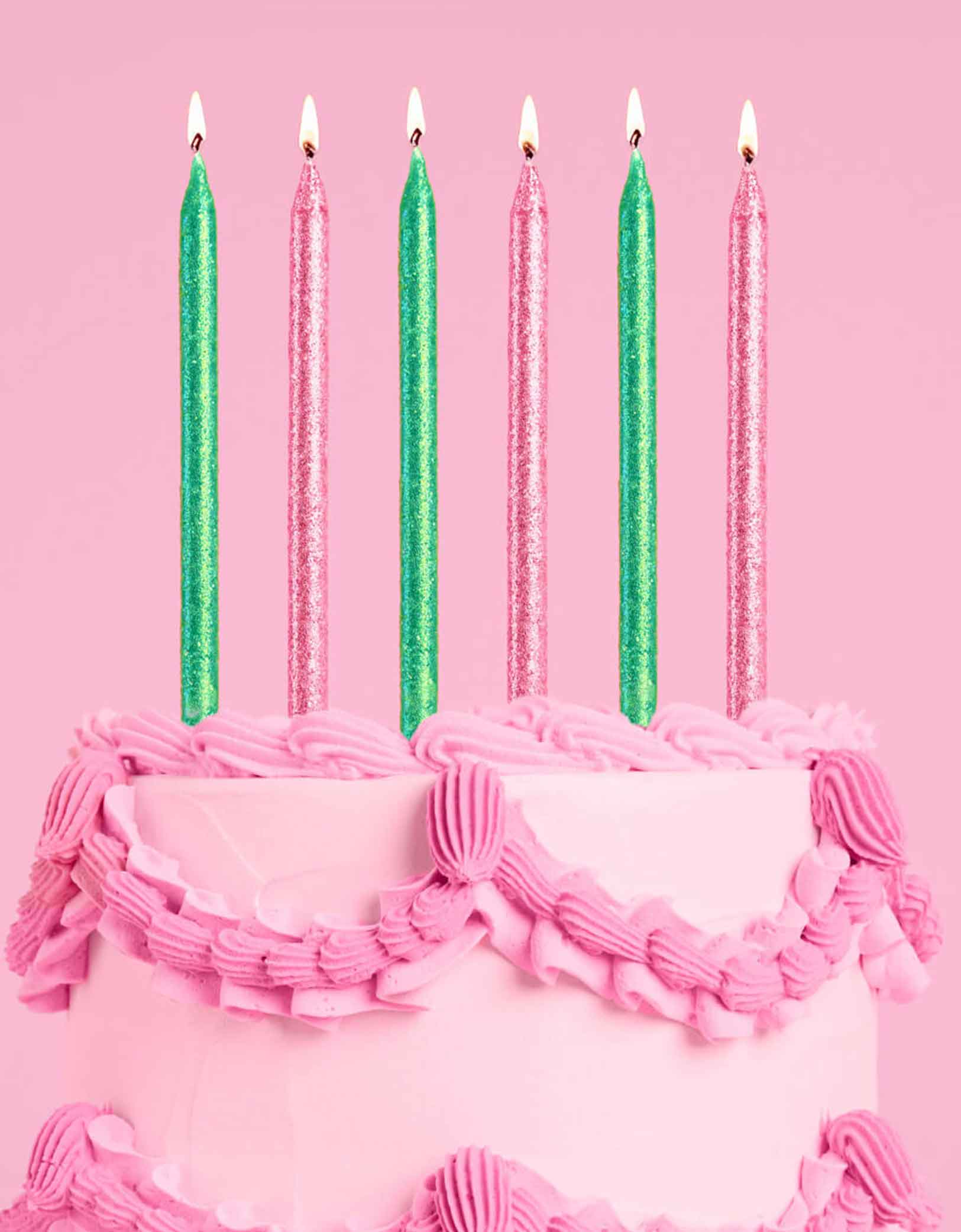 A pink buttercream cake with Momopartys's Wicked Party Emerald City Glitter Candles in pink and green by Xo, Fetti on a pink background.