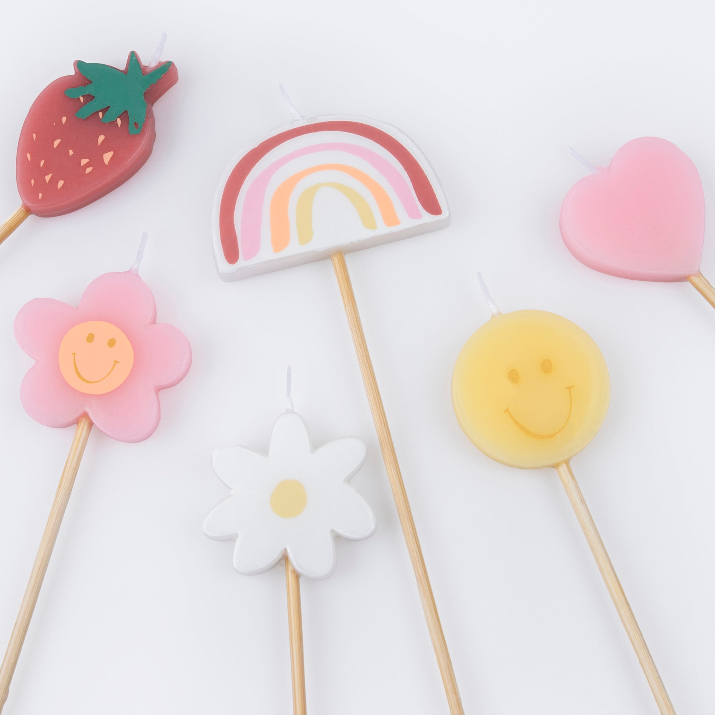 Details of Momopartys's Happy Face Icons Candles by Meri Meri. Featuring a set of 6 strawberry, a flower, a daisy flower, a rainbow, a smiley face, and a heart candle with long sticks, these colorful candles are perfect for any happy celebration!