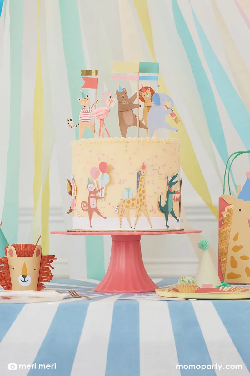 Momopartys Animal Parade themed birthday party table, with a cake decorated with Animal Parade Cake Wrap & Toppers, a lion cup from Animal Parade Character Cups set on the left, and a giraffe party bag from the Animal Parade Party Bags on the right side of the table. These modern and cute design party supplies from Meri Meri of Animal Parade Collection are perfect for kid's zoo, safari, or jungle themed birthday party, or even baby's "Wild One" first birthday party or a "Two Wild" second birthday party!