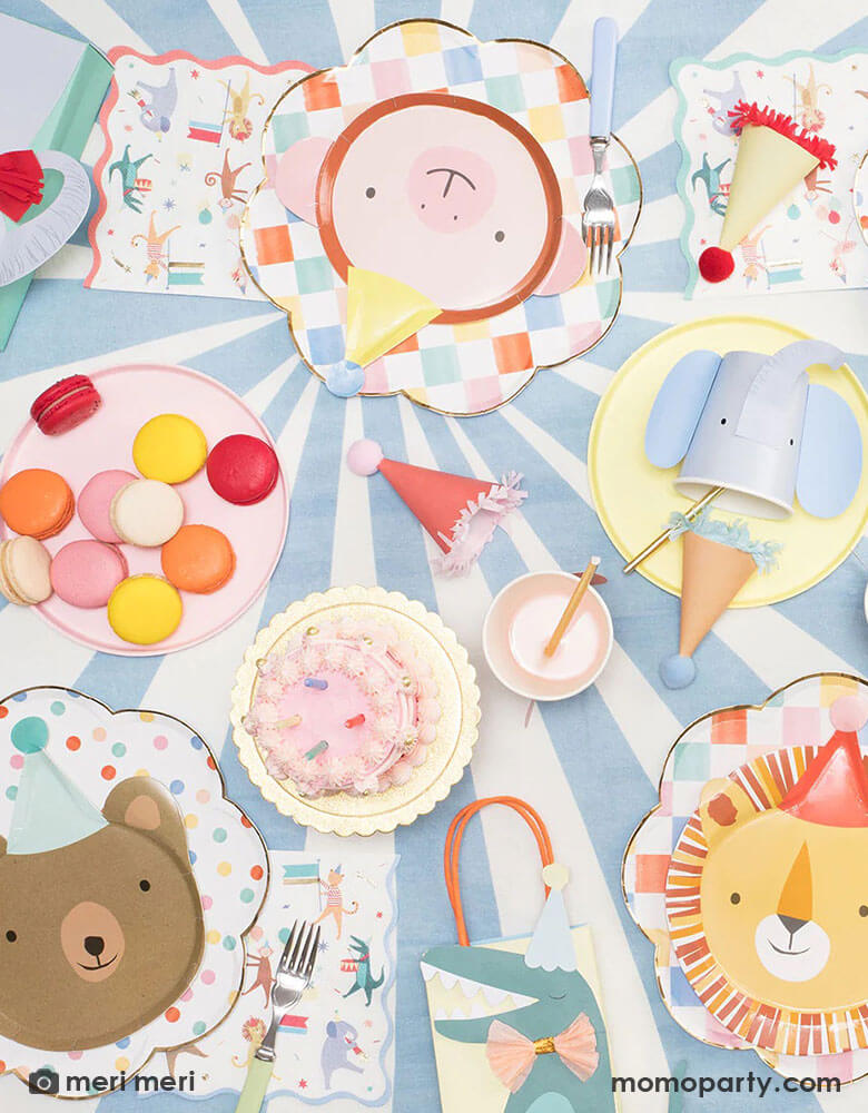 A flatlay photograph of a festive party animal themed party table filled with Momopartys's Animal Parade collection including animal die-cut plates, animal shaped party cups, Animal Parade party bags and Animal Parade large napkins by Meri Meri.
