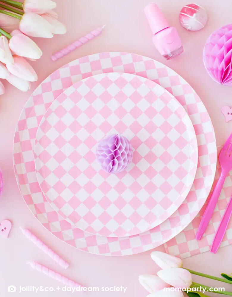 A beautiful set pink table featuring Momopartys's Check it! Pink Check it! Collection by Jollity & Co. including pink checkered patterned dinner plates, dessert plates, and large pink checkered napkins, around the tableware, it was decorated with some pretty tulips, pink nail polish bottle, some pink birthday candles and honeycomb decorations. All in all makes a great inspiration for a girly themed celebration.