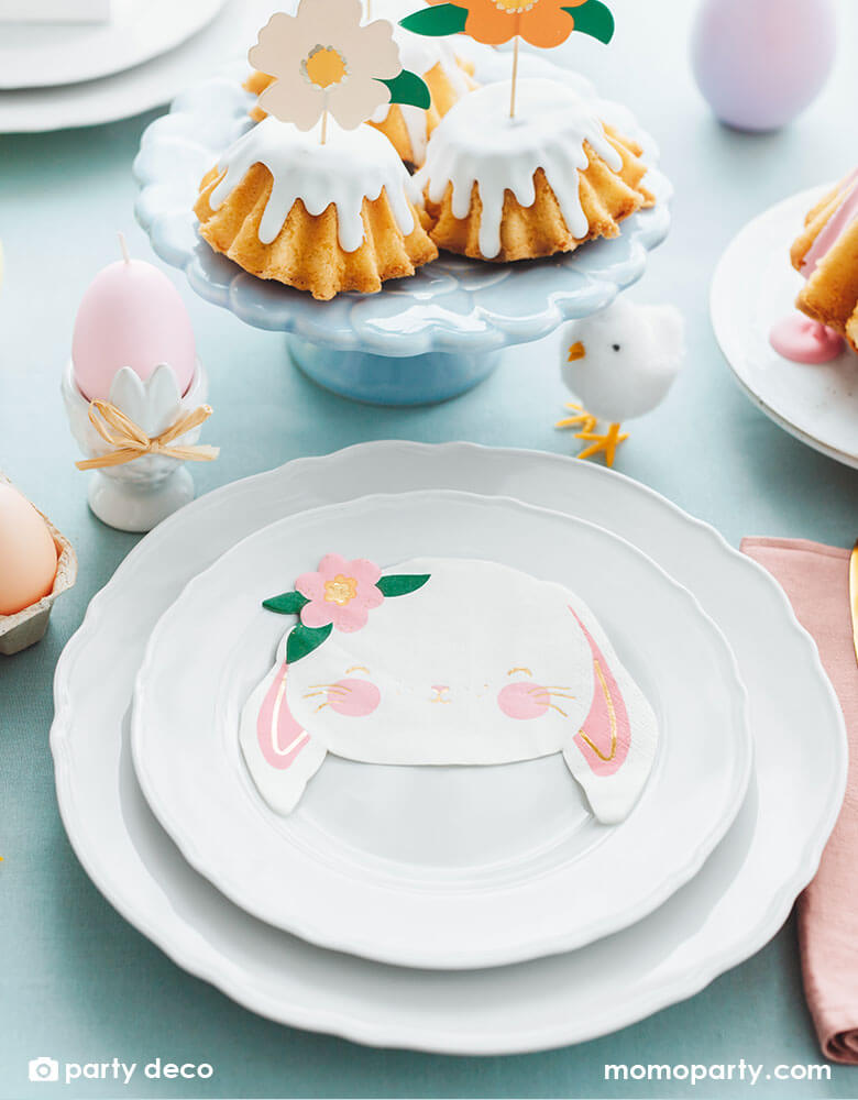 An adorable tablescape featuring Momopartys's floral bunny napkins by Party Deco on two sets of white plates, around them were Momopartys's 2.75" Easter chicks decorations and Easter egg shaped candles. On the table there's some bundt cakes topped with floral cake toppers - all make a beautiful Easter brunch table.
