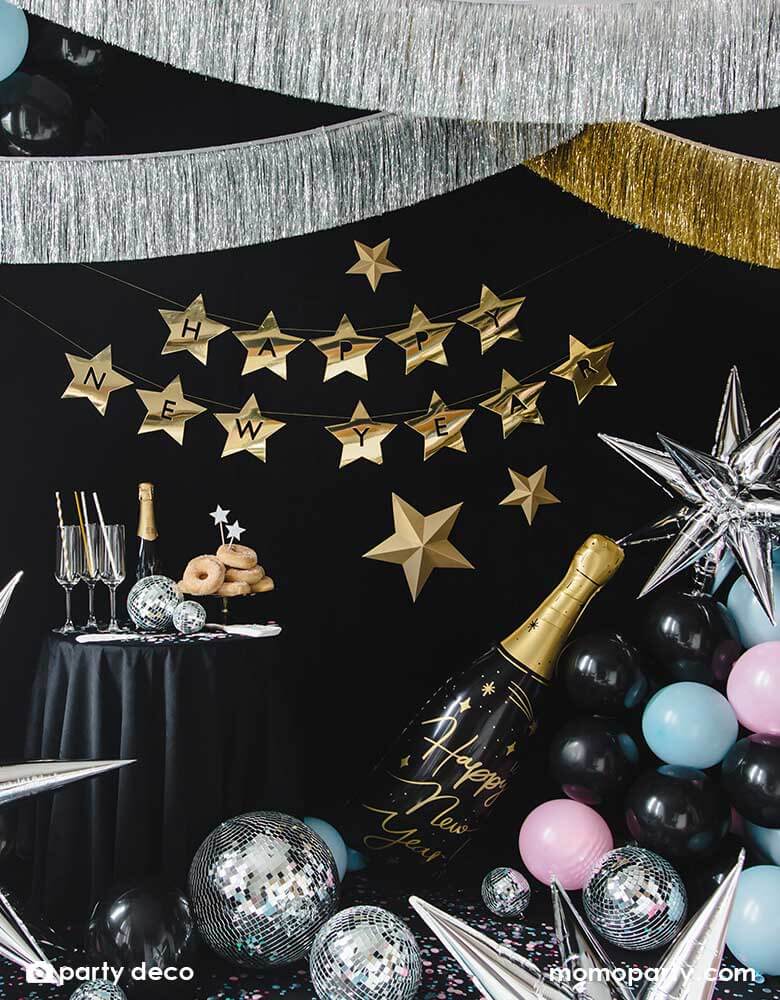 A New Year's Eve countdown party decorated with Momopartys's gold and silver tinsel garlands and various Happy New Year themed balloons including a champagne bottle shaped foil balloon, silver starburst balloons, and disco ball decorations 
