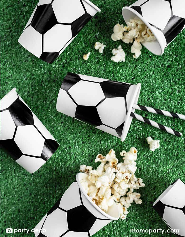 A table with Momopartys's 6.8 oz Soccer ball party cups by Party Deco in classic black and white color, perfect for a kid's soccer themed birthday party or a World Cup soccer watching party!