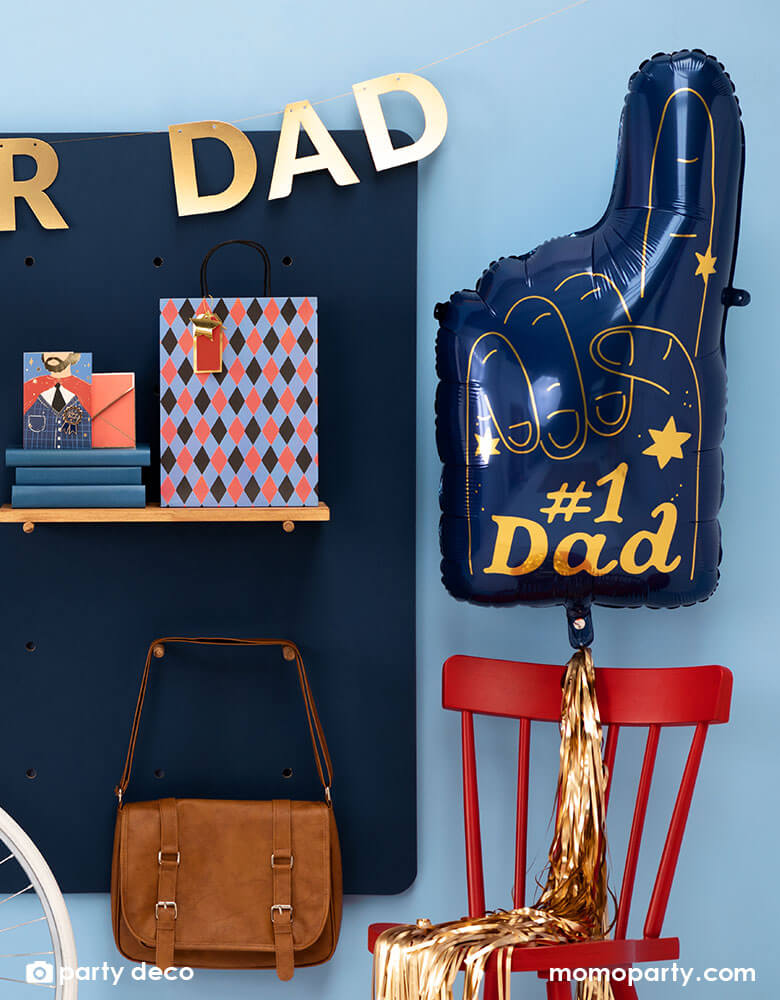 A wall decorated with cool Father's Day gifts, along side is Momopartys's 34 x 18" blue #1 Dad Finger Shaped foil balloon by Party Deco, featuring gold foil accent, it's perfect for a special Father's Day celebration.